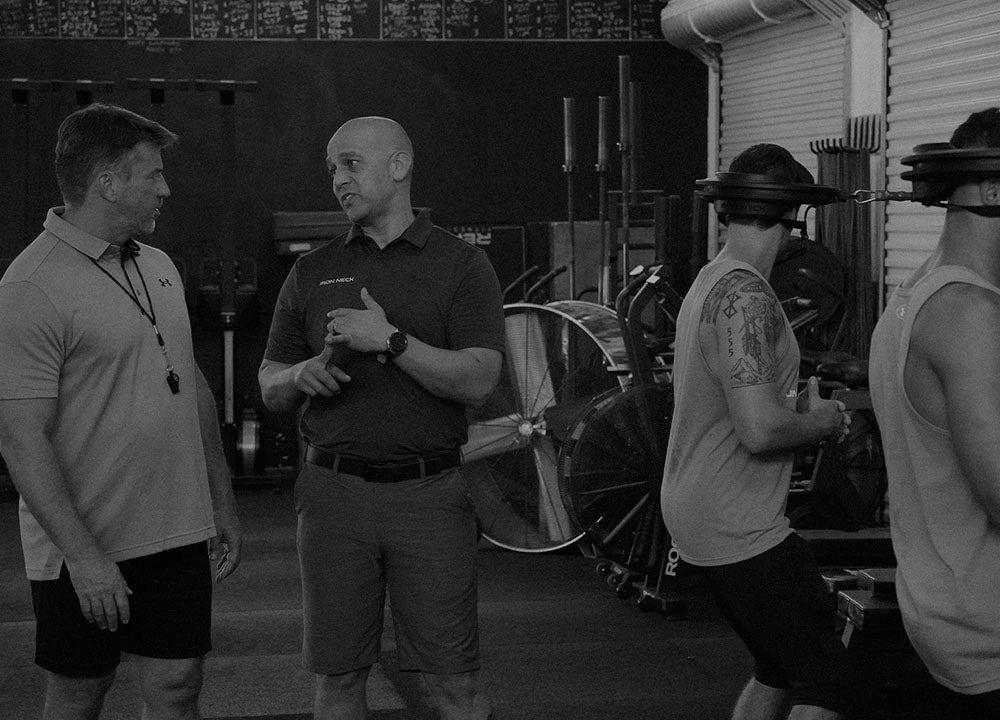 Iron Neck Trainer explaining to coach how to use Iron Neck with his athletes